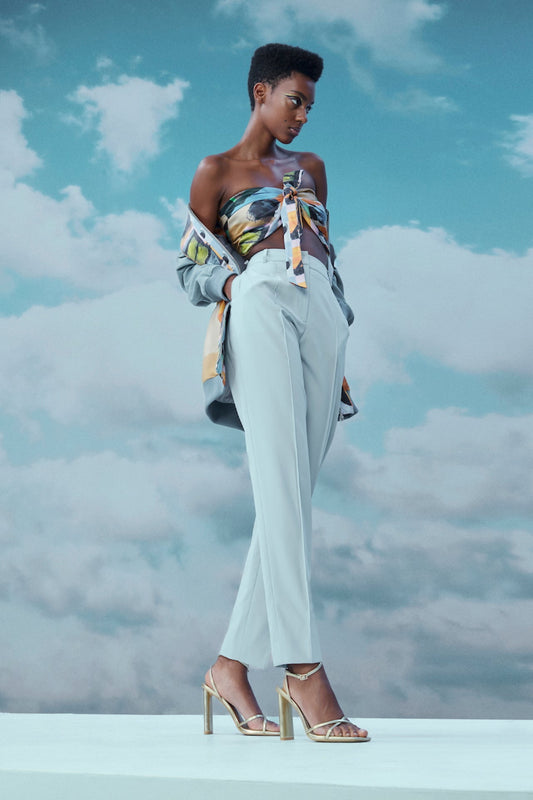 Woman in stylish outfit against a cloudy sky