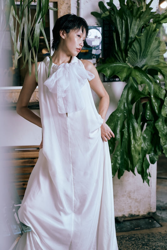 Woman in a white dress standing among plants indoors